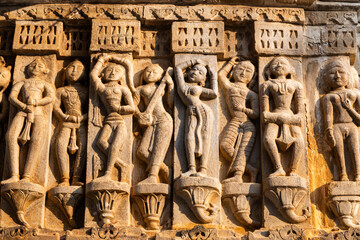 Sculptures of musicians and dancers on hindu holy temple wall at golden hour