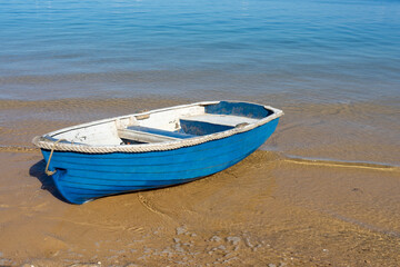 Blue and white row boat on the sandy shore of the calm blue sea. Main Beach, Coochiemudlo Island, Queensland, Australia