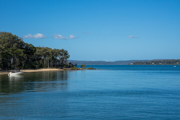 View across calm water to the sandy shore of Coochiemudlo Island, with Macleay Island and Stradbroke Island in the distance.