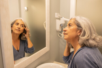 Portrait of senior retired woman in bathroom looking in mirror