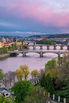 Bridges over Vltava river against pink sky seen from Letna park at sunset, Prague, Bohemia, Czech Republic