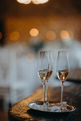 Two glasses of champagne on table on blurred background. Wedding, party, celebratory toast.