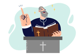 Elderly priest with bible in his hands stands behind pedestal with christian crucifix