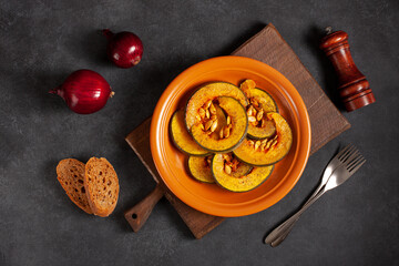 Delicious baked pumpkin on a brown plate, onion, bread and spices, top vew. Homegrown organic eco food. The concept of Thanksgiving. The concept of proper healthy nutrition