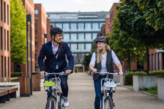 Spouses commuting through the city, riding bike on street. Middle-aged city commuters traveling from work by bike after a long workday.