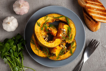 Pumpkin baked in the oven, toasts, herbs, garlic and spices on a gray background, top vew. The concept of healthy eating. The concept of Thanksgiving. Concept vegetarian food 