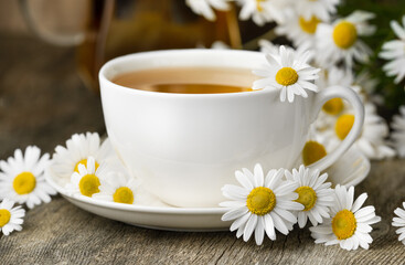 white mug with chamomile tea on a wooden table