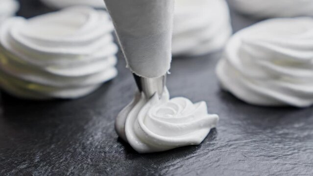 Process of making Cake Anna Pavlova. Confectioner makes meringue for cake. Baker spread meringue on baking sheet with a pastry bag. Close-up in 4K, UHD