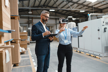 Warehouse managers talking logistics using VR, controlling stock levels. Virtual reality in inventory management. Smart glasses guiding female manager through warehouse, recording tracking data and