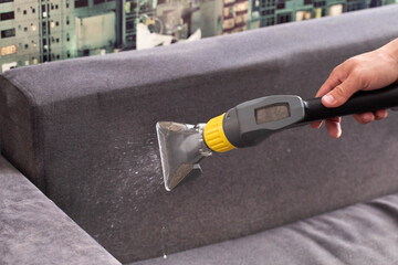 Dry cleaning of the black upholstery on the sofa with a special washing vacuum cleaner. Copy space...