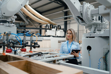 Female engineer in modern industrial factory, checking robotic arm, controling process and manufacturing equipment or machinery. Manufacturing facility with robotics and automation.