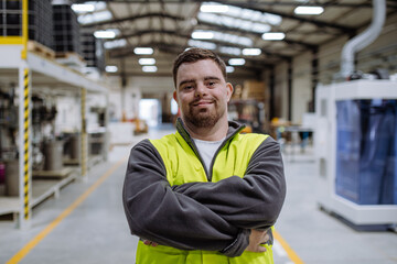 Portrait of young man with Down syndrome working in warehouse. Concept of workers with disabilities, support in workplace. - obrazy, fototapety, plakaty