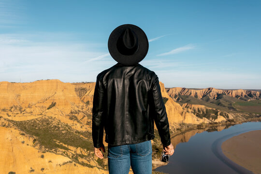 Explorer in hat facing a scenic river canyon landscape
