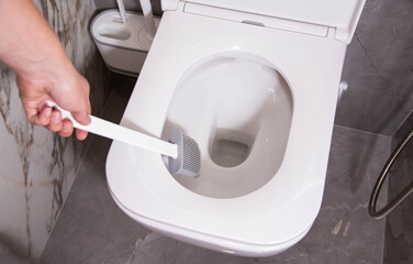 Modern silicone brush for cleaning the dirt of the wall-mounted toilet. Toilet care and hygiene concept, close-up