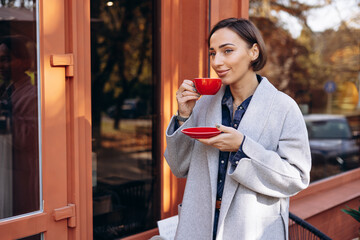 Woman drinking hot coffee outside coffee shop