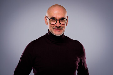Obraz premium Bald mid aged man wearing turtleneck sweater and standing against isolated grey background