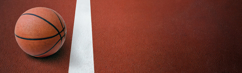 Basketball ball is sitting in the red rubber court vertical white line outdoors, top view. copy space.image for sport, exercise concept.High quality image.Banner.