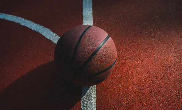 Basketball ball is sitting in the red rubber court vertical white line outdoors, top view. copy space.image for sport, exercise concept.High quality image.