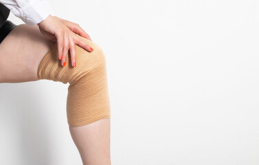 The girl puts on an elastic orthopedic knee pad on a sore leg. Arthrosis and knee injury. Fixation...