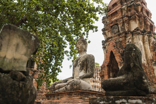 Old Buddha statue and ruined ancient prang at temple in Thailand