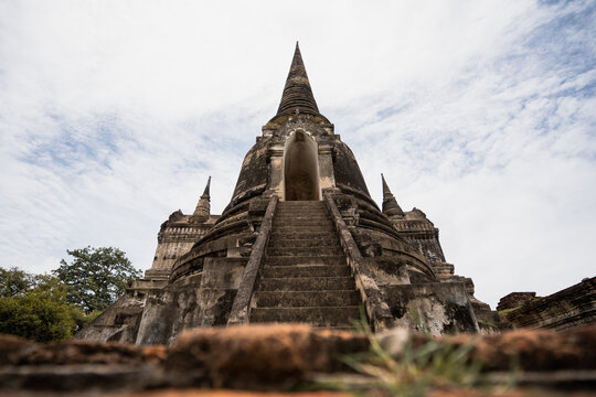Ancient Buddhist Thai temple against cloudy sky in Thailand