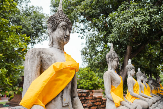 Stone Buddha statues covered with yellow cloth in Thailand