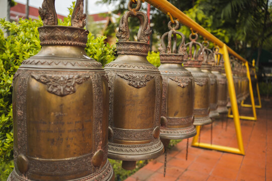Row of bells hanging in ancient Buddhist temple in Thailand