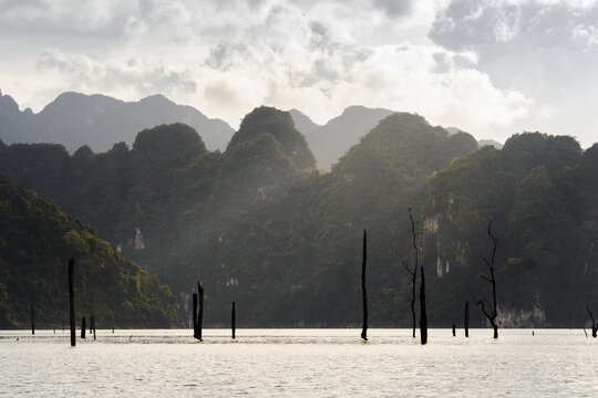 Cheow Lan Lake surrounded by mountains in sunlight in Thailand