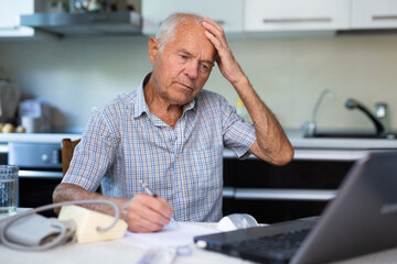 Elderly man is learning how to use a laptop at home