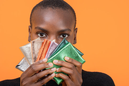 Black woman with colorful wallets isolated over orange background
