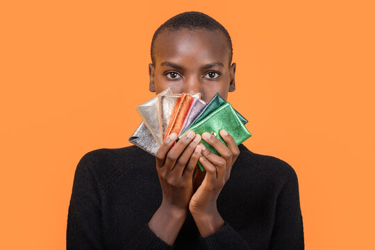 Black woman with colorful wallets isolated over orange background