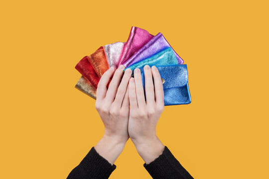 Woman holding colorful wallets against yellow background