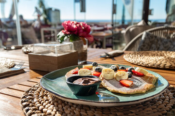 a close up image of a plate of freshly made pancakes topped with fresh fruit and chocolate at a mediterranean beach bar
