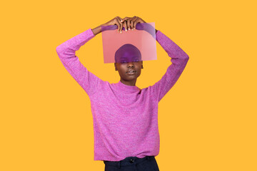 Black woman in warm clothing holding transparent plastic on yellow background