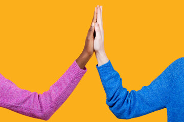 Anonymous multiracial women touching hands over yellow background