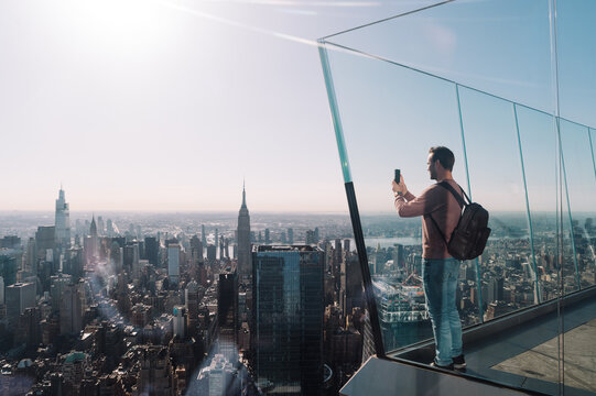 Man photographing Manhattan cityscape in sunlight