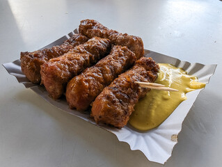 Mici with mustard and a toothpick on a paper plate. Traditional romanian fast food.