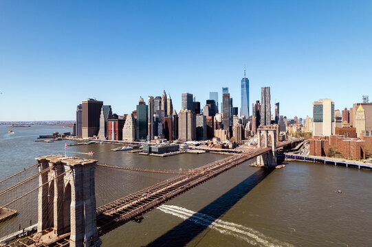 Brooklyn Bridge with city skyline backdrop under blue sky.