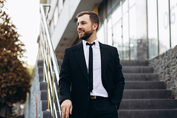 Handsome business man in black suit walking down the stairs by office center