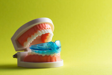Dental mouth guard for bruxism with a mock-up of a dental jaw on a yellow background. Concept for...