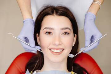 Portrait of smiling caucasian lady and cropped dentist hands in blue gloves with tools in hands