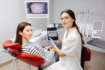 Dentist and patient choosing treatment in a consultation with tablet in dental office