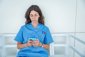 Young female nurse browsing smartphone while sitting on bench