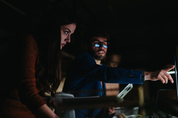 Diverse business team collaborates on project deadline, analyzing reports and discussing strategies for growth and profitability.