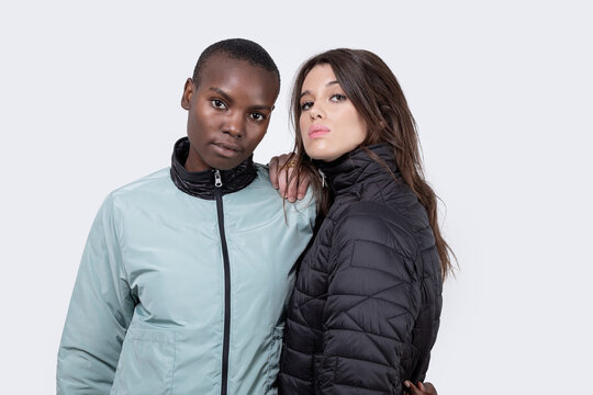 Confident diverse female friends in jackets over white background