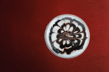 Top view of iced mocha coffee latte art chocolate flower shape spiral glass on red background