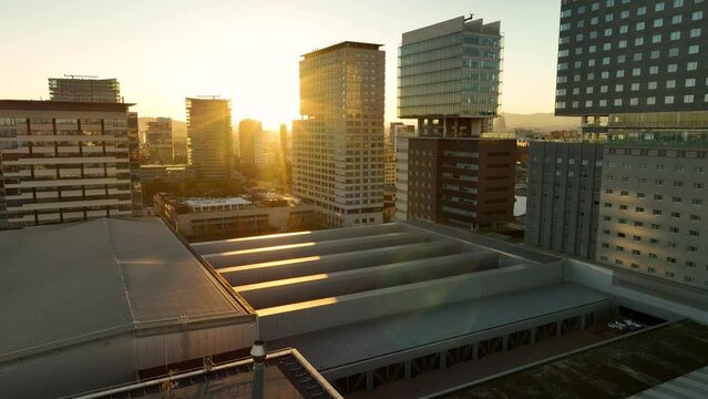 Aerial view of Barcelona at sunset with high skyscrappers and wide panorama of the city on the background. Landscape and architecture. Drone flying over Forum Park and Diagonal Mar. Spain, Europe.