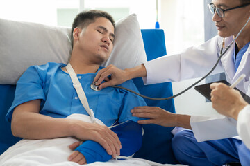 An Asian male patient lies in a hospital bed and is carefully looked after by a doctor. Doctor giving advice to male patient Working on health disease diagnosis