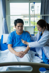 Fototapeta premium An Asian male patient lies in a hospital bed and is carefully looked after by a doctor. Doctor giving advice to male patient Working on health disease diagnosis