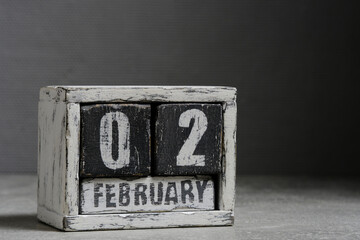 February 02 on wooden calendar, on dark gray background.